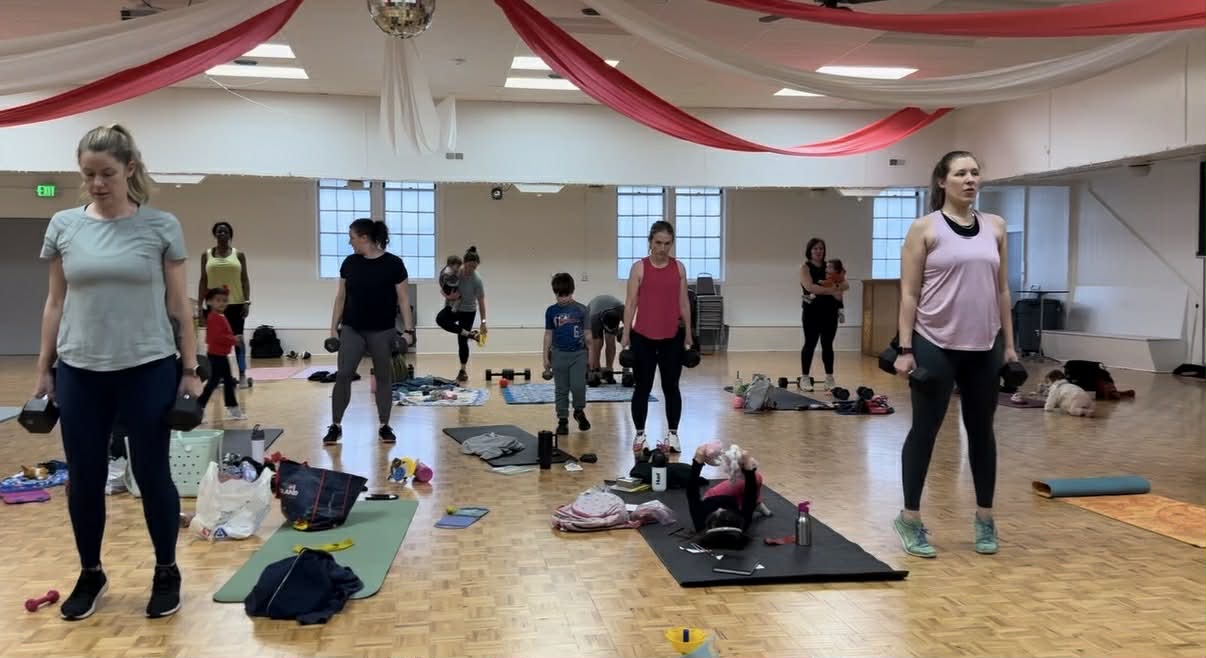 Large indoor class with members and kids working out together