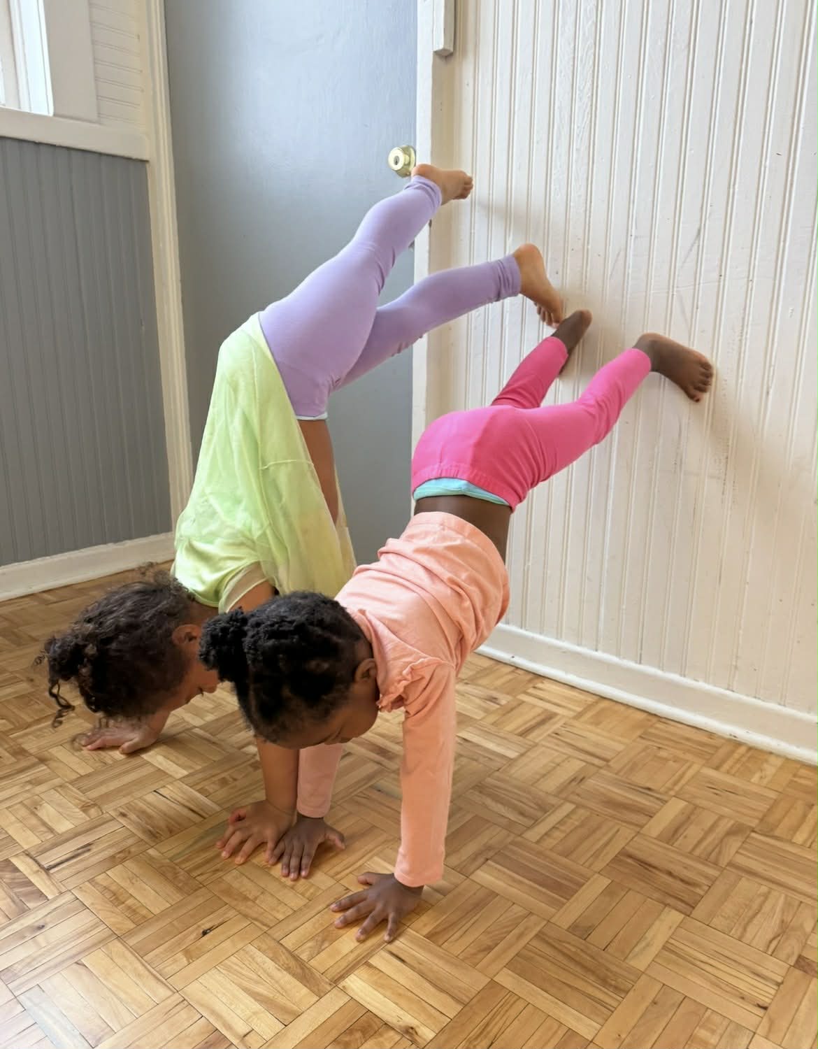 Two kids doing handstands against the wall during class
