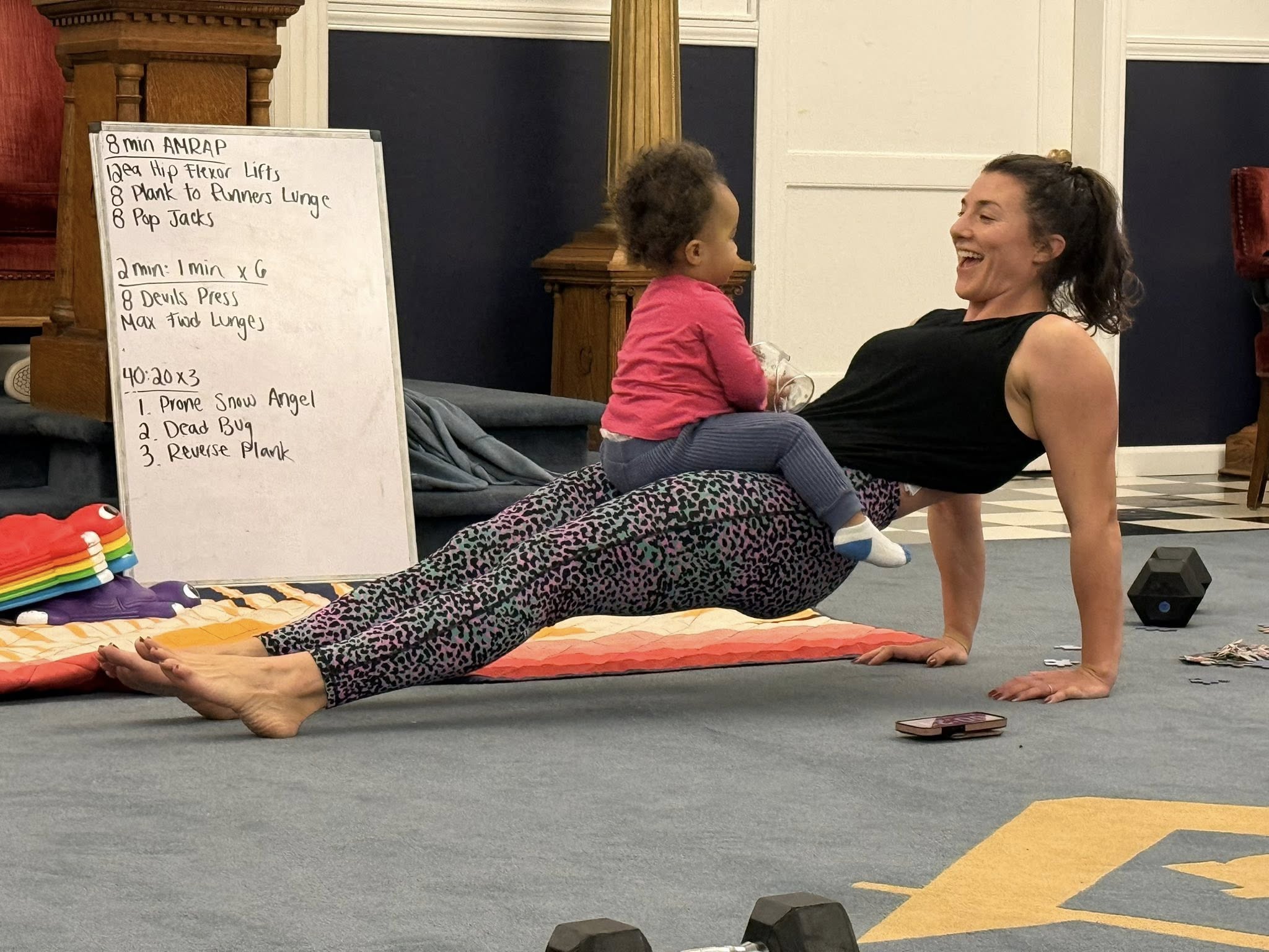 Member doing plank exercise with child nearby